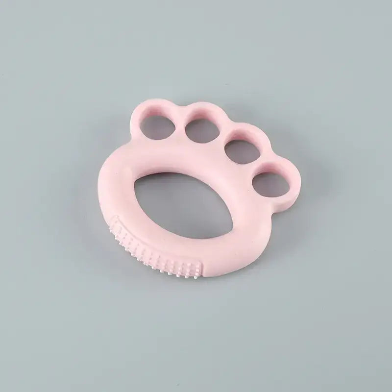 Pink silicone baby teether shaped like a paw print with textured ridges along the bottom edge.