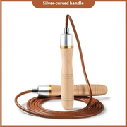 A jump rope with a silver-curved handle, light wood grips featuring subtle engraved lines, and brown leather cord.