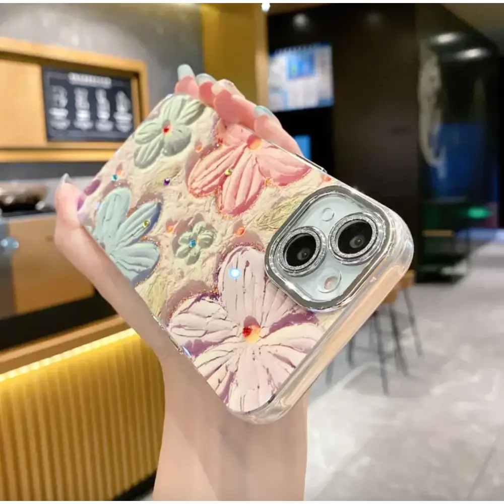 A clear phone case adorned with raised pastel flowers in pink, mint green, and lavender hues, accented by tiny colorful rhinestones.