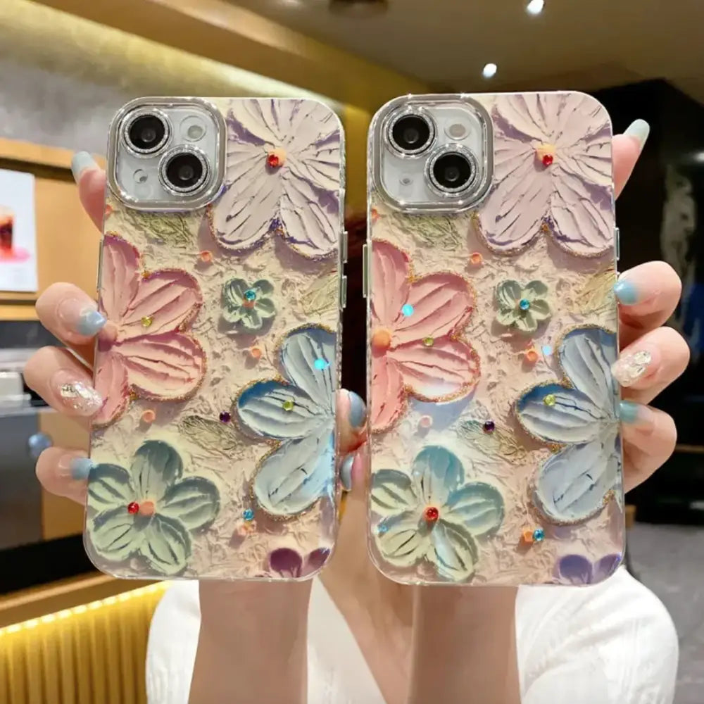 Pastel-colored floral phone case with raised, painted blossoms in pink, blue, and green hues adorned with tiny gemstones.