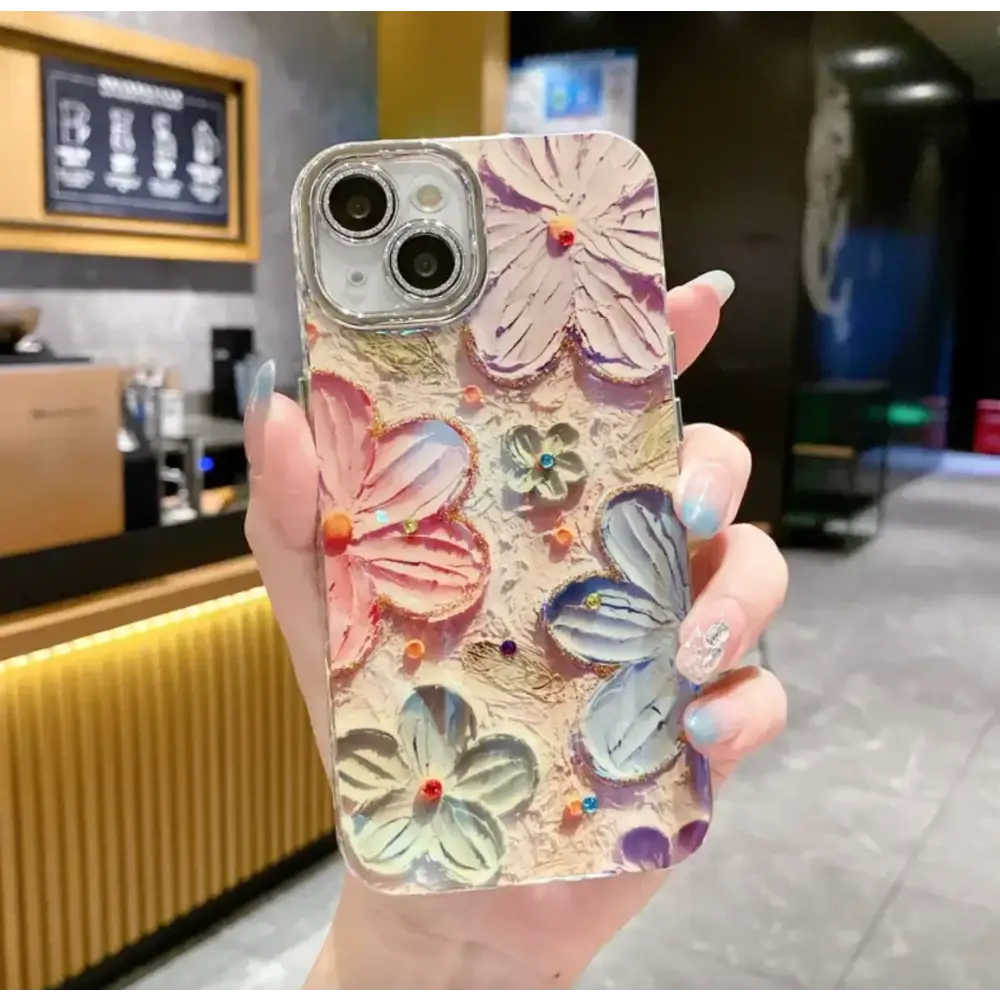 A translucent phone case adorned with raised, colorful 3d flowers in pink, purple, and blue hues, each accented with tiny gemstones.