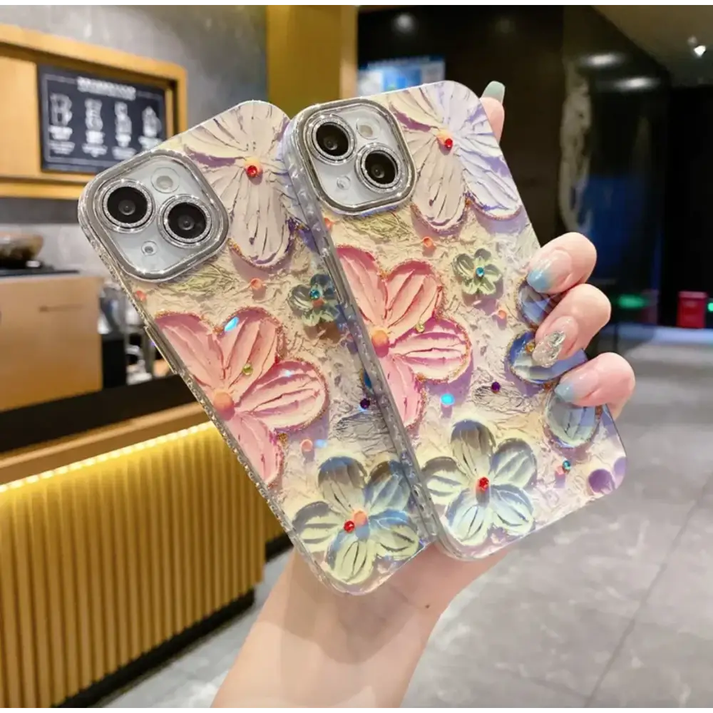 A translucent phone case adorned with raised, colorful 3d flowers in pink and blue hues, each accented with tiny gemstones.