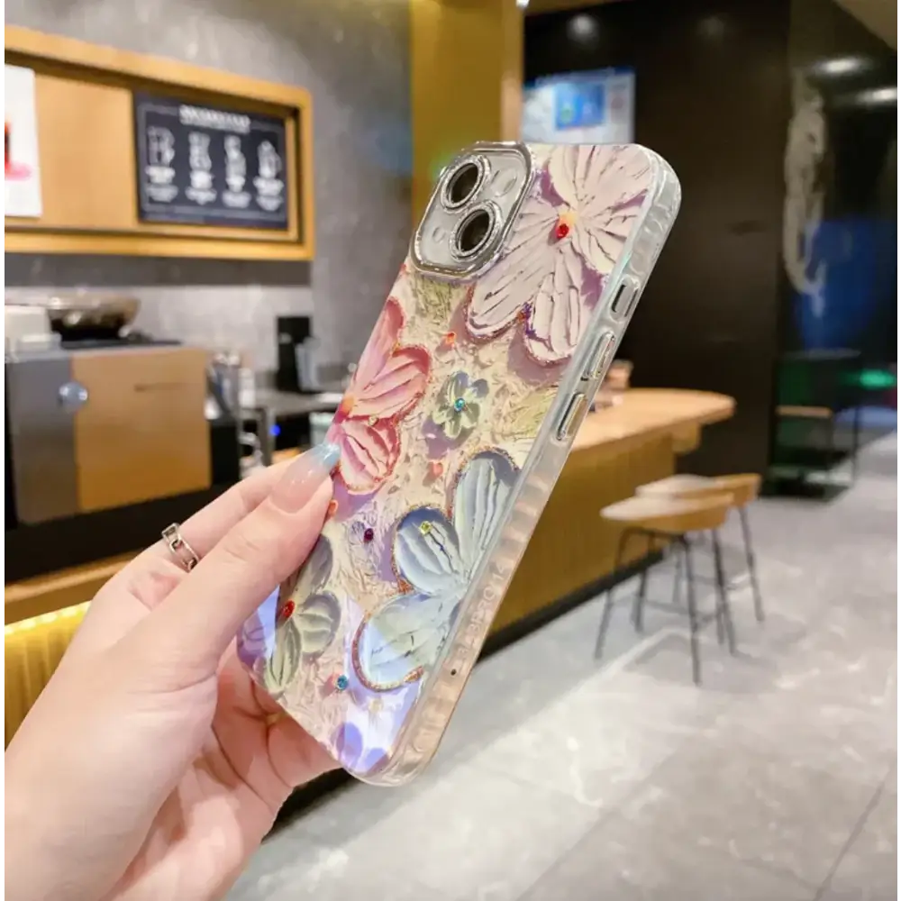 A transparent phone case adorned with raised, colorful floral and butterfly designs accented by small gemstones.