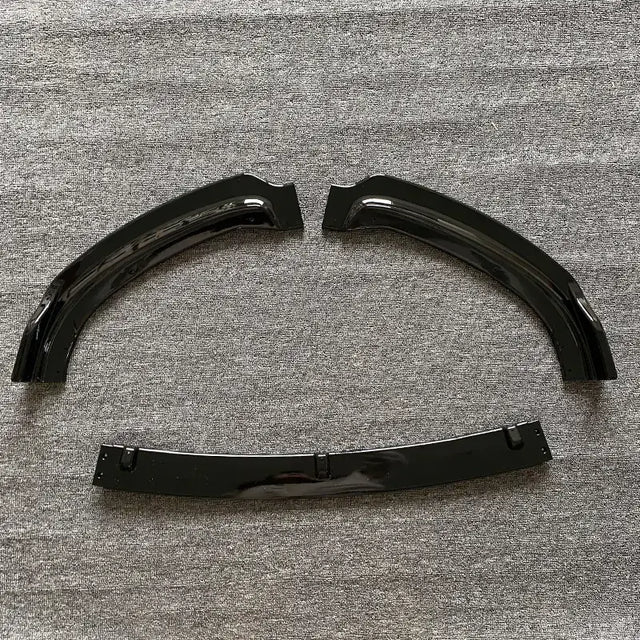 Black glossy plastic fender liners with a curved, arched design and mounting brackets.