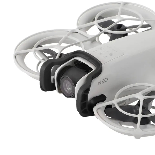 White and black drone with protective cage design, featuring a mounted camera lens.