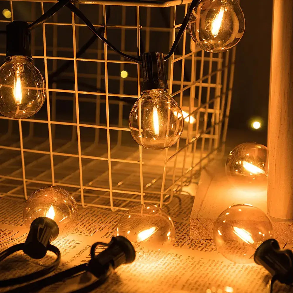 Warm, glowing globe-shaped string lights with clear glass bulbs and black plastic sockets.