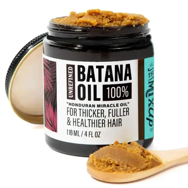 Unrefined batana oil in a dark glass jar with a white and teal label, containing a golden-brown paste-like substance.
