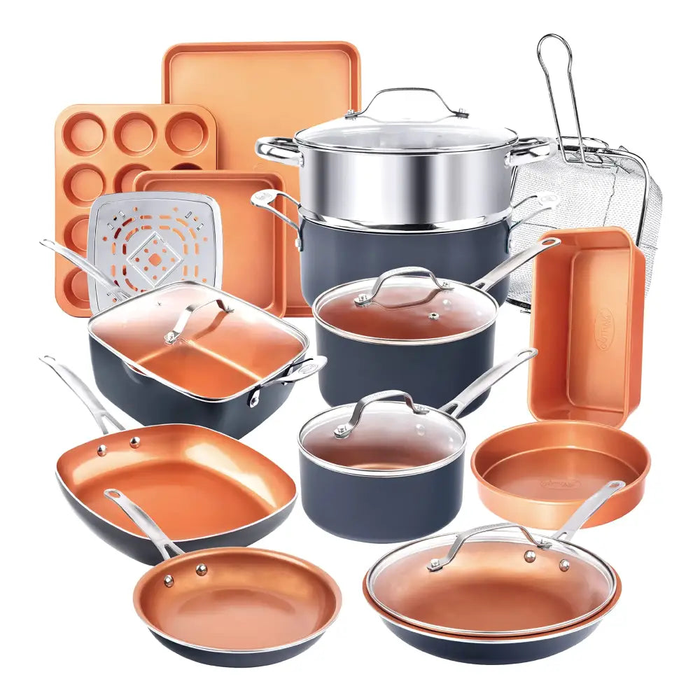 Copper-finished nonstick cookware set with dark blue exteriors and stainless steel handles, featuring glass lids and various baking trays.