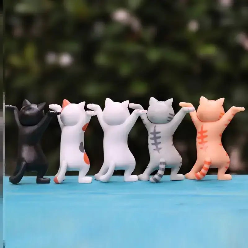 Five adorable, stylized cat figurines in various colors and patterns stand together with arms raised.