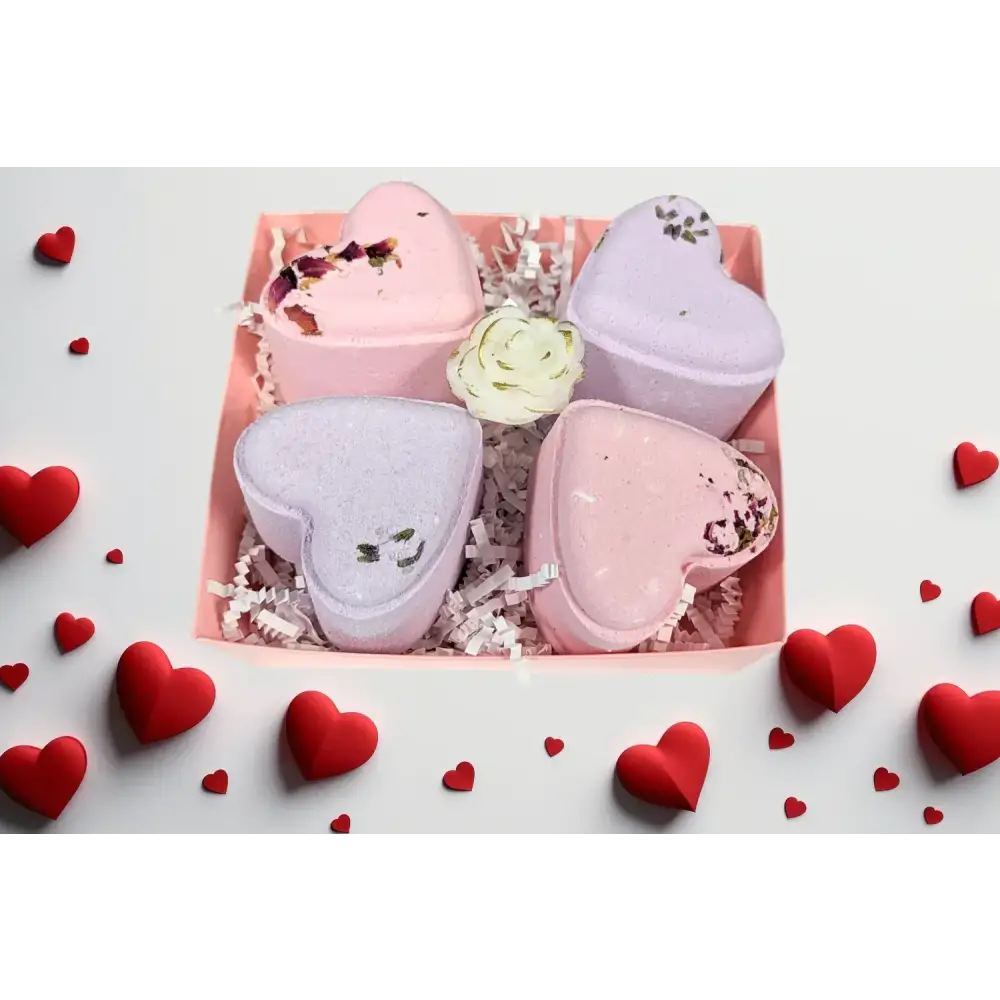 Pink and lavender heart-shaped bath bombs with floral accents nestled in a pink box.