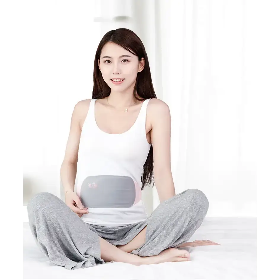 Gray and pink maternity support belt worn by a woman sitting cross-legged.