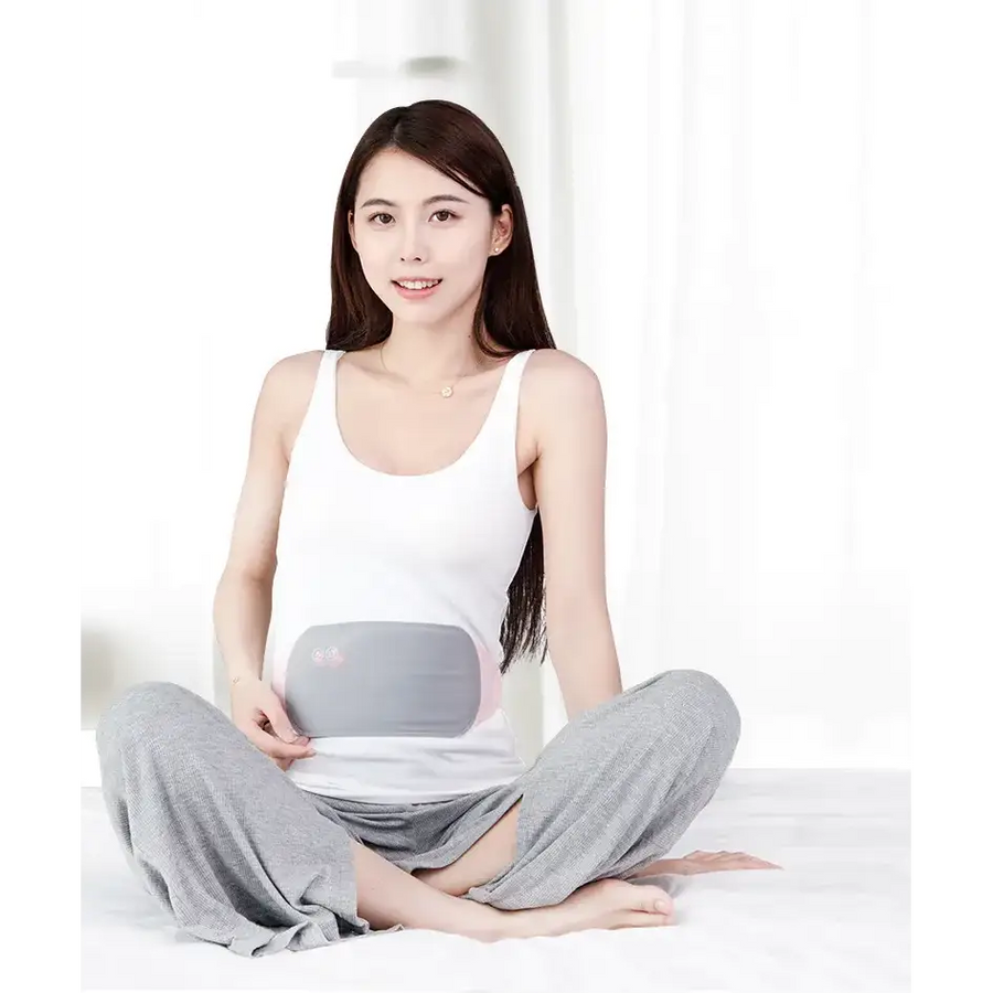 Gray and pink maternity support belt worn by a woman sitting cross-legged.