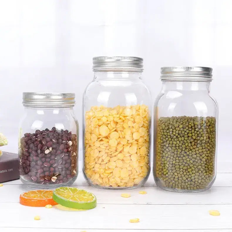 Three clear glass mason jars with silver metal lids, each filled with different types of dried legumes.