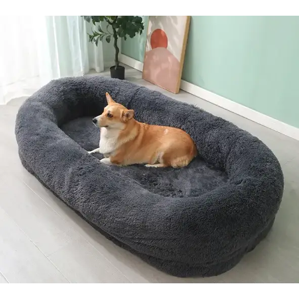 A cozy, dark gray plush dog bed with a soft, fluffy texture and an oval shape.