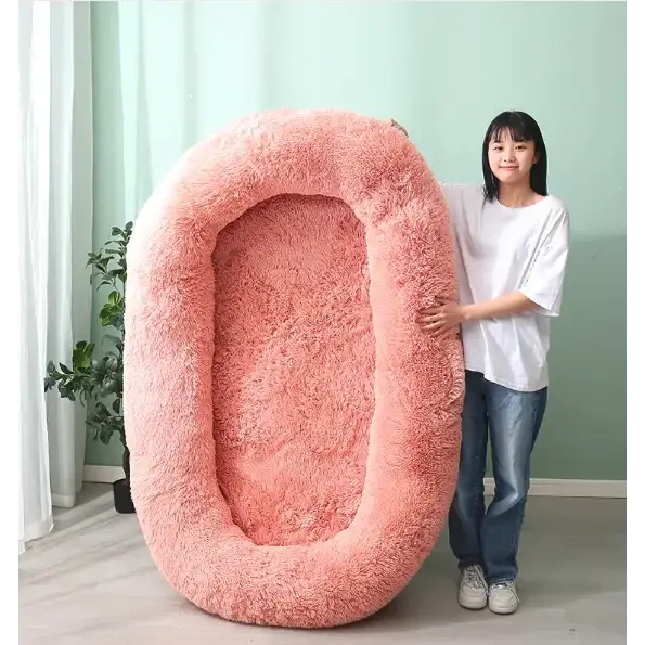 A plush, pink, oval-shaped pet bed with a soft, shaggy texture.
