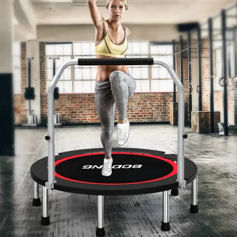 Black and red circular trampoline with silver metal frame and handlebars, branded ’boomg’ on the mat.