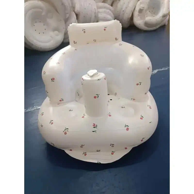 White inflatable baby seat with a floral pattern of small red and green flowers.