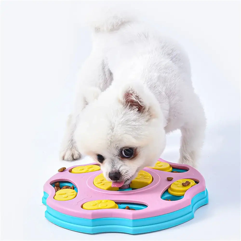 Pink and blue plastic dog puzzle feeder with yellow paw-shaped inserts