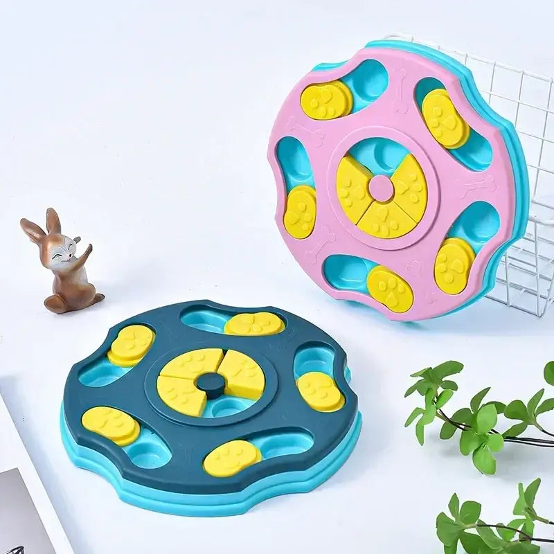 Pink and blue plastic pet puzzle feeder with yellow paw-print shaped slots.