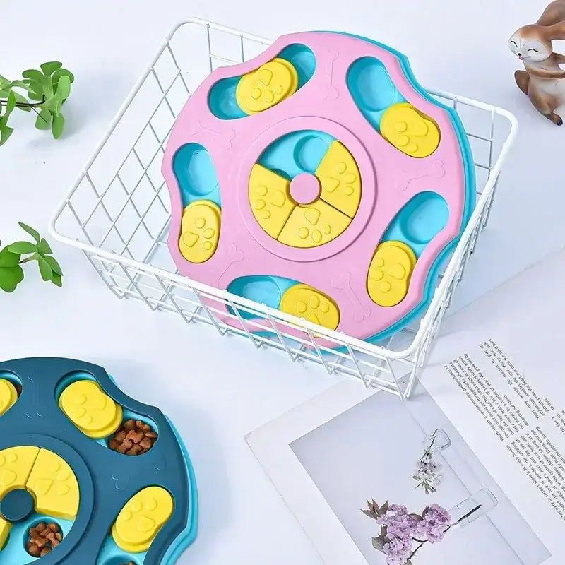 Pink and blue plastic pet puzzle feeder with yellow paw-printed levers.