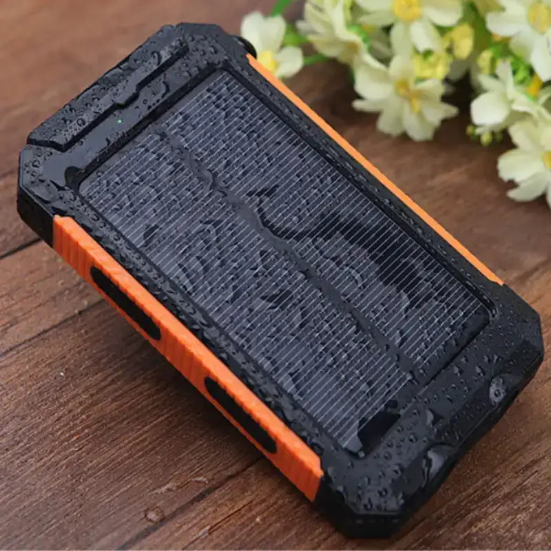 Black and orange rugged solar-powered portable charger with a textured, water-resistant design.