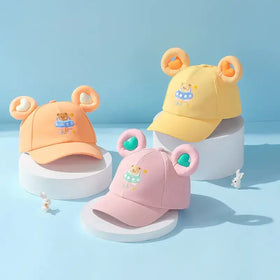 Pastel-colored toddler baseball caps with plush bear ears and embroidered teddy bears in swimwear