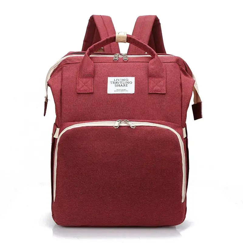 A maroon fabric backpack with beige zipper pulls and trim, featuring a white label that reads ’living traveling share.’