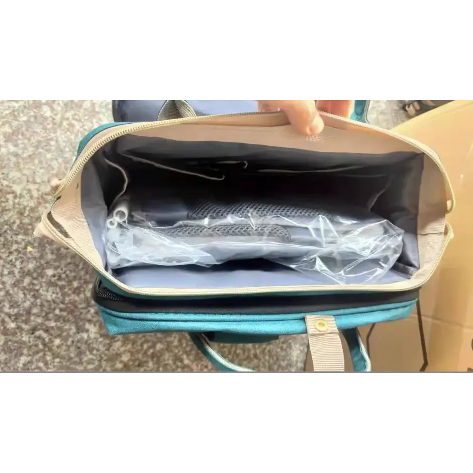 Teal and beige diaper bag with a zippered opening revealing an organized interior.
