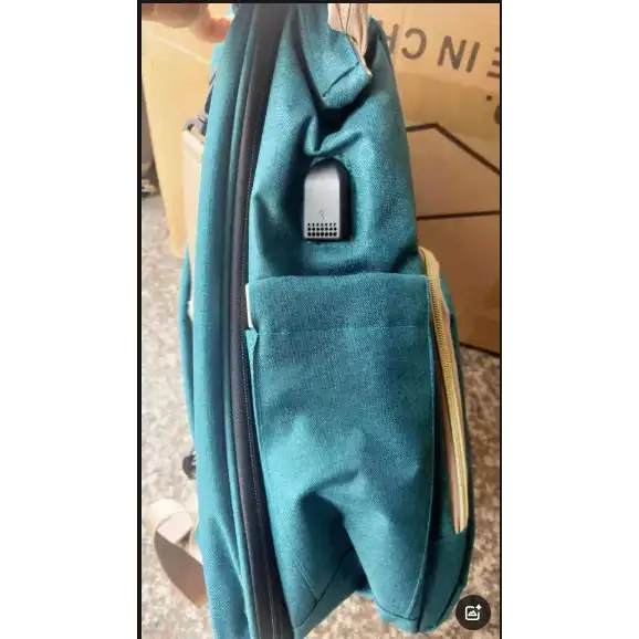 Teal fabric backpack with a built-in usb charging port on the side.