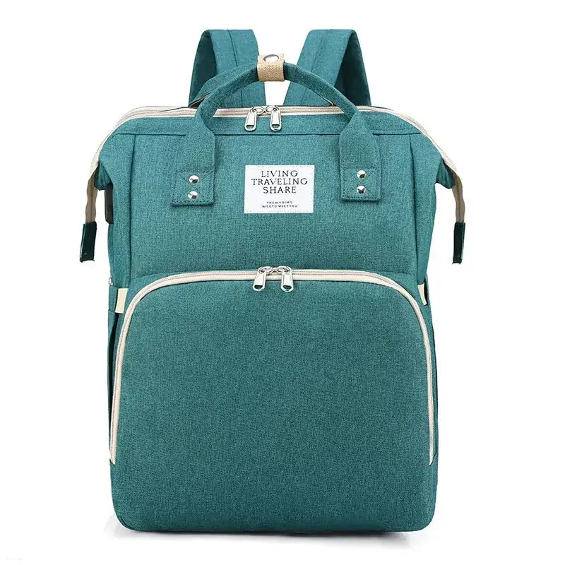 Teal fabric diaper bag with beige zipper pulls and silver-toned hardware, featuring a front pocket and top handle.