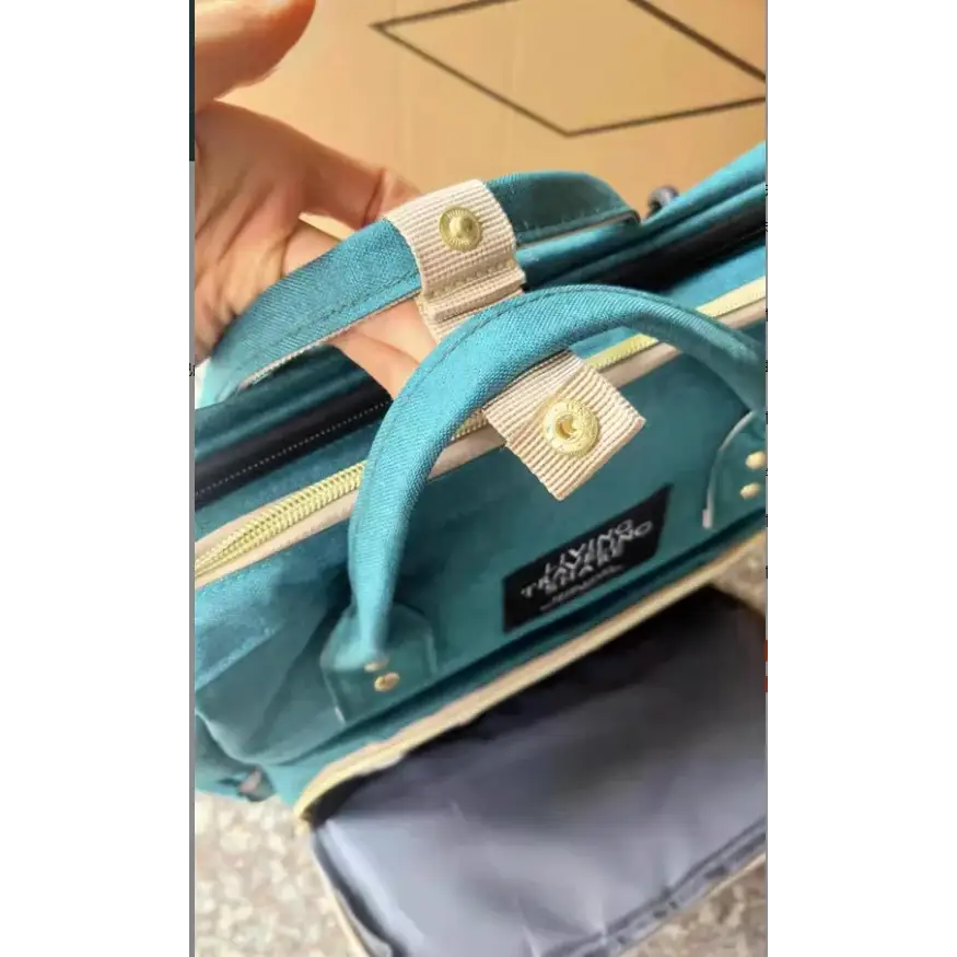 Teal velvet diaper bag with beige fabric straps and gold-tone metal hardware.