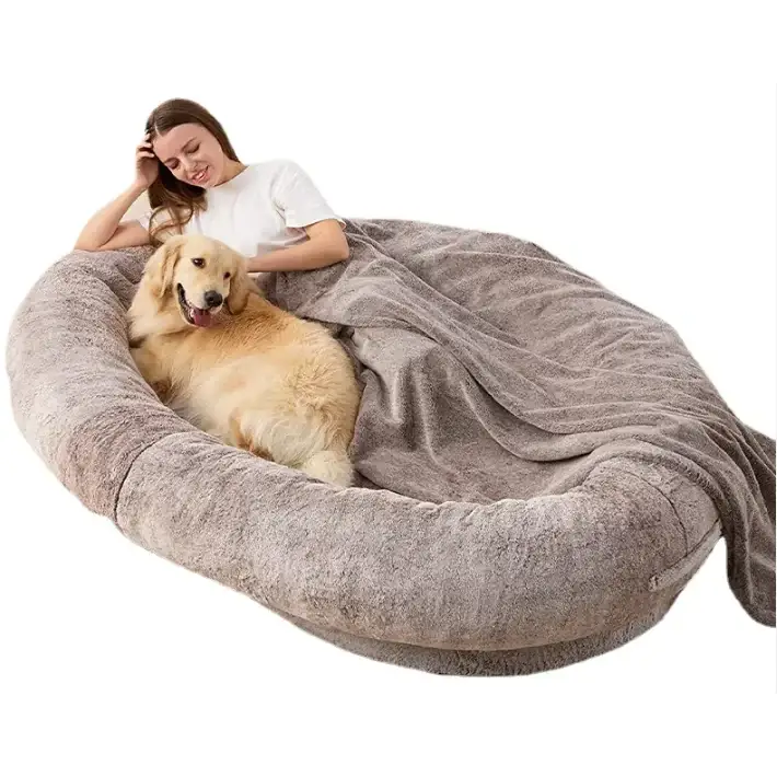 A plush, gray, oval-shaped dog bed with a soft, fleece-like texture and an integrated blanket.