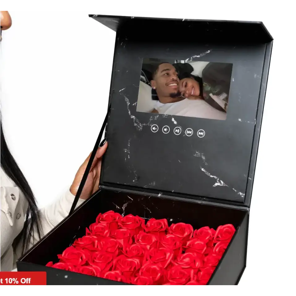 Black marble-patterned box with a built-in screen displaying a photo, filled with vibrant red artificial roses.