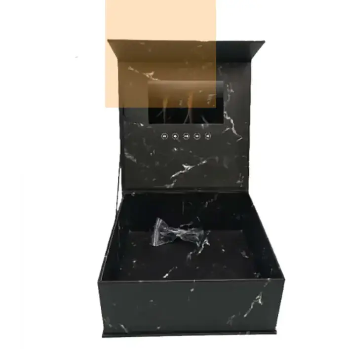 Black marble-patterned gift box with a built-in screen and control buttons, containing a clear plastic-wrapped bow tie.