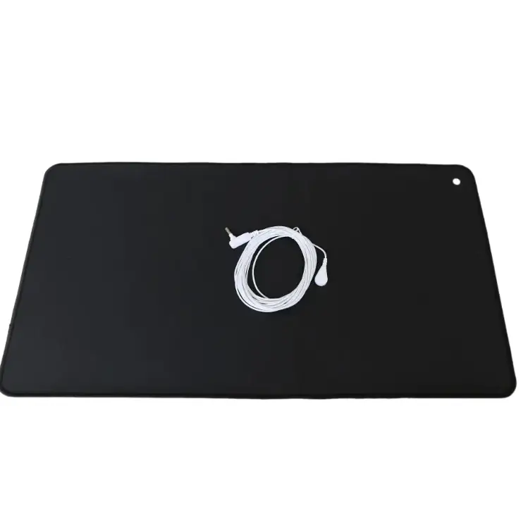 Black rectangular heating pad with coiled white cable and plug resting on its surface