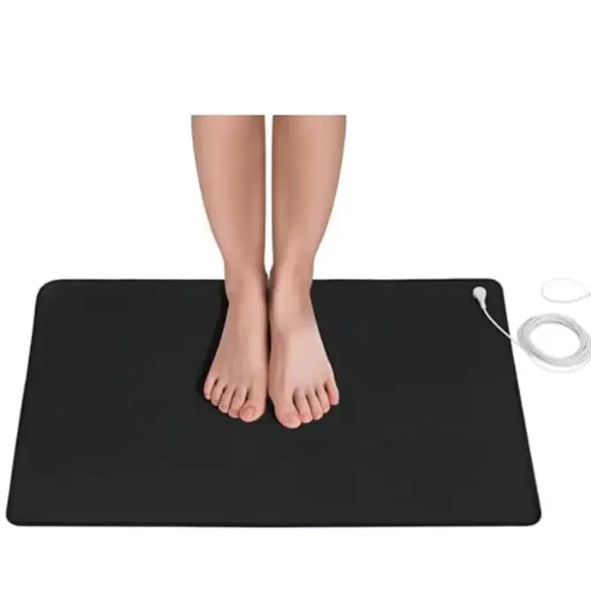 Black rectangular electric heating mat with a white power cord coiled nearby.