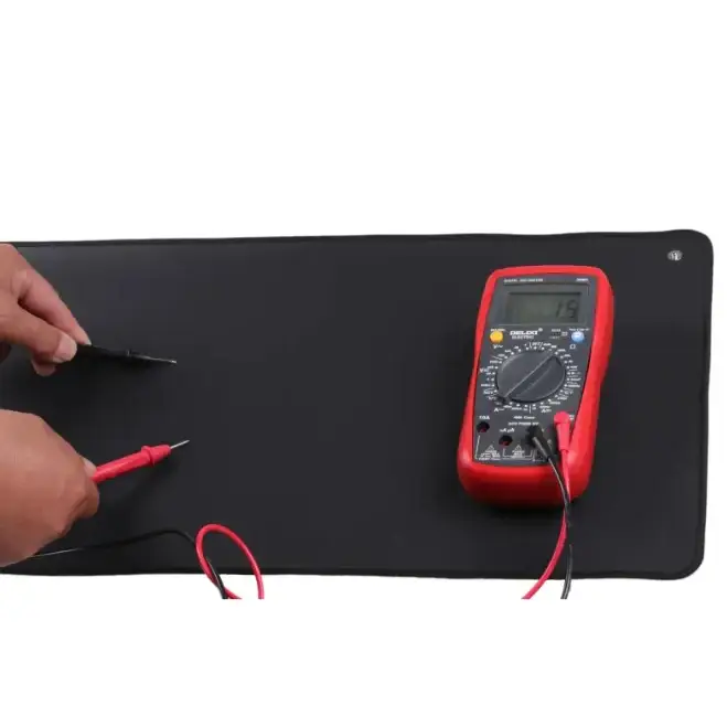 Red digital multimeter with black display and probes resting on a black mat