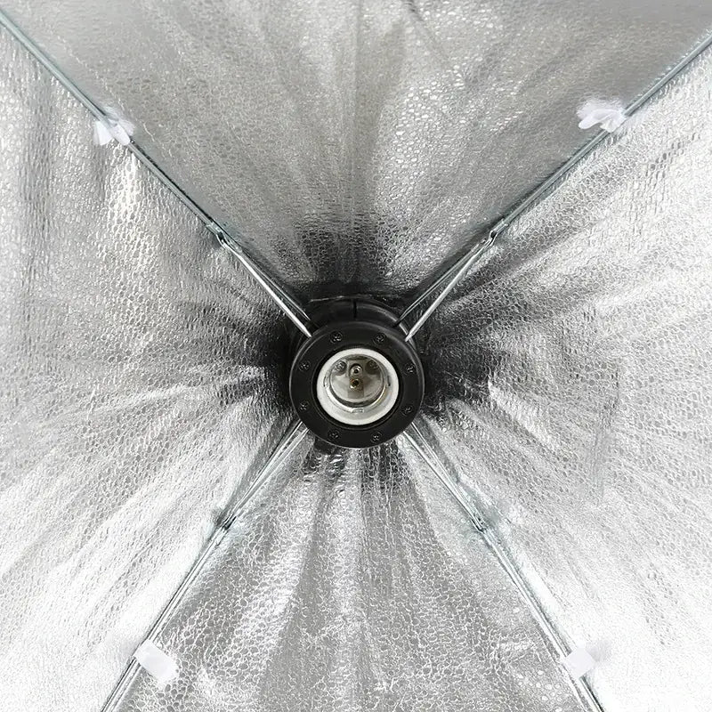 Silver reflective interior of a collapsible studio light umbrella with metal frame and central bulb socket.