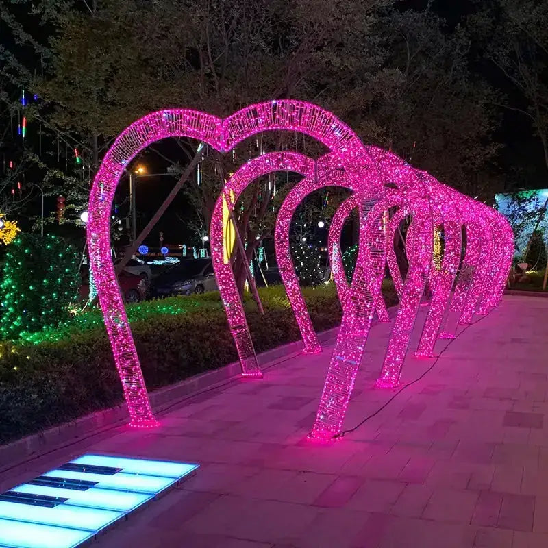 A series of glowing pink heart-shaped light arches, each constructed from a framework wrapped in sparkling led lights.