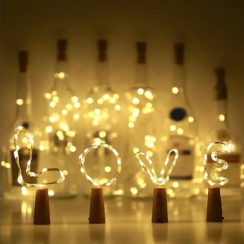 Warm white led string lights shaped into the word ’love’ are displayed on cork bottle stoppers.