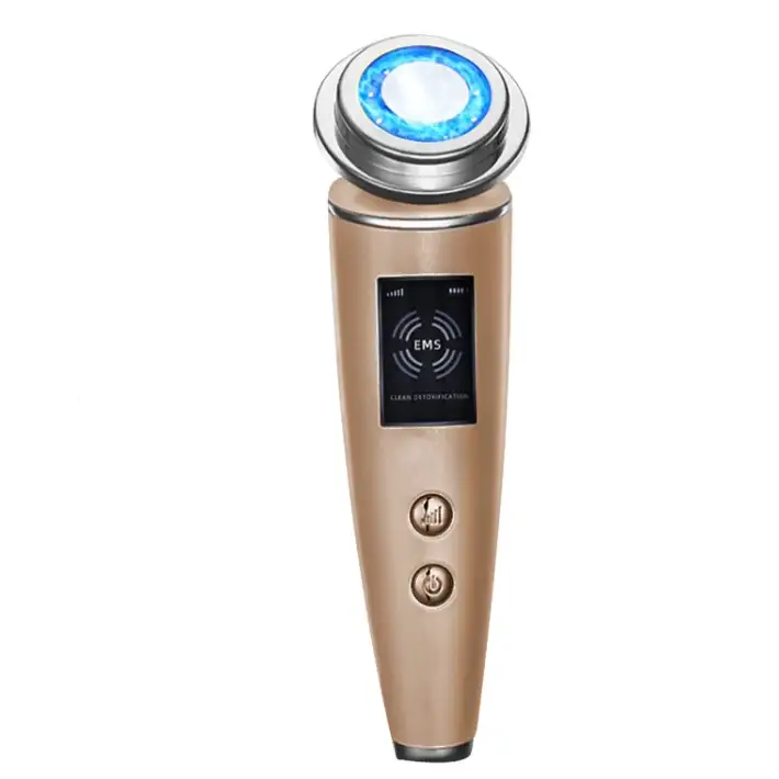 Gold-toned handheld facial device with a glowing blue circular treatment head and a digital display showing ’ems’ for clean detoxification.