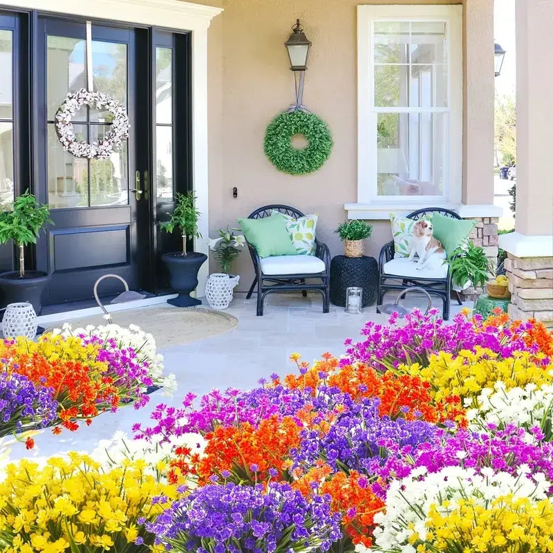 A vibrant, colorful flower bed bursting with purple, orange, yellow, and white blooms arranged in a lush, dense pattern.