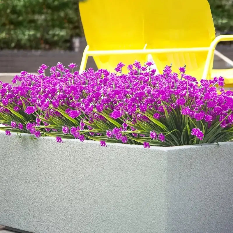 A vibrant purple flowering plant with slender green stems and leaves, overflowing from a textured gray rectangular planter.