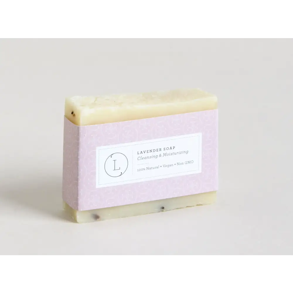 A rectangular bar of pale lavender soap with a subtle speckled texture, wrapped in light purple paper featuring a minimalist label.