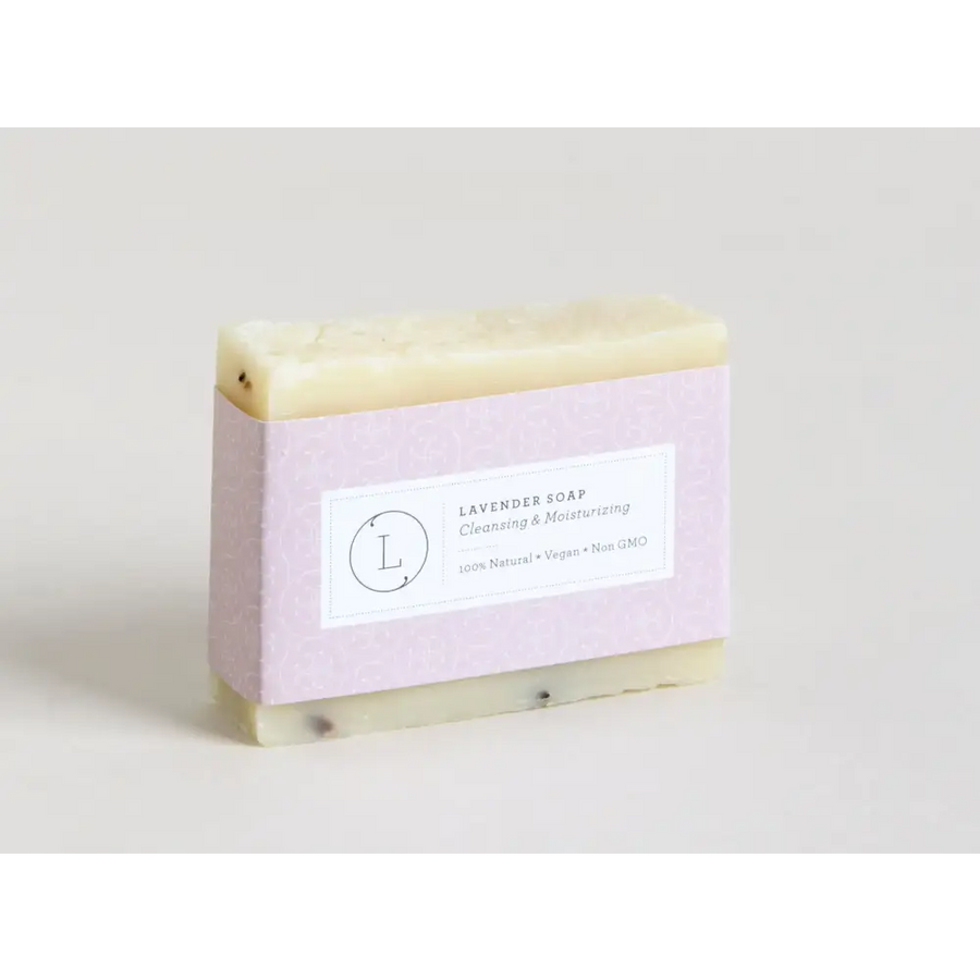 A rectangular bar of pale lavender soap with a subtle speckled texture, wrapped in light purple paper featuring a minimalist label.