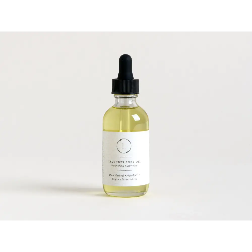 A clear glass bottle with a black dropper cap contains pale yellow lavender body oil, labeled as ’100% natural • non-gmo • vegan • essential oil.’