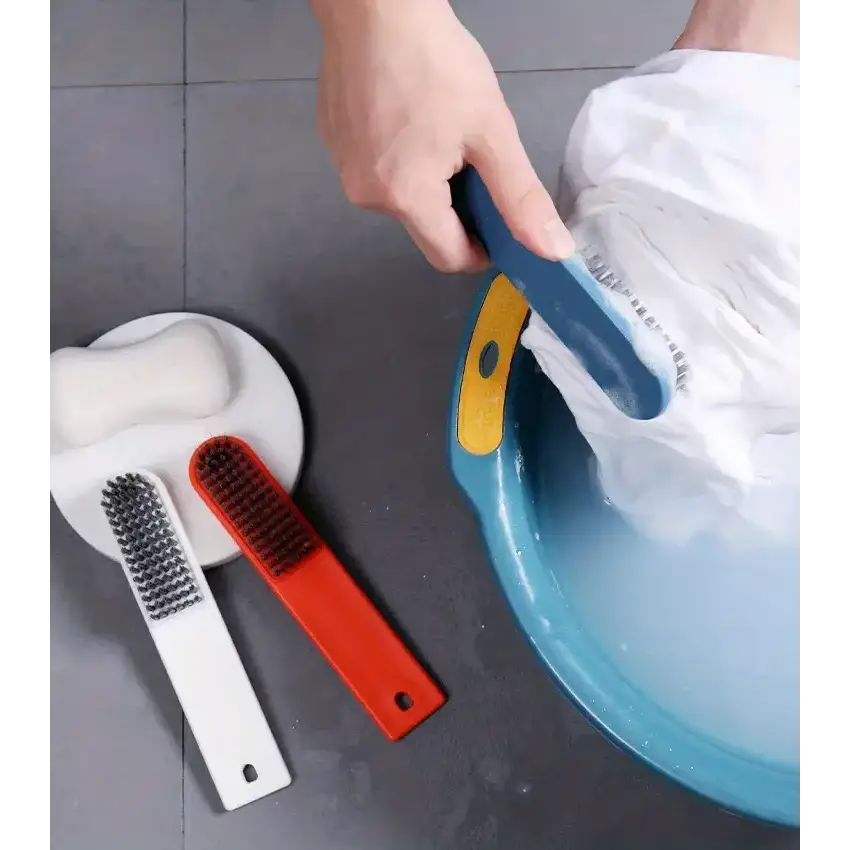 Blue and yellow scrub brush with a curved handle being used to clean white fabric in a blue basin.