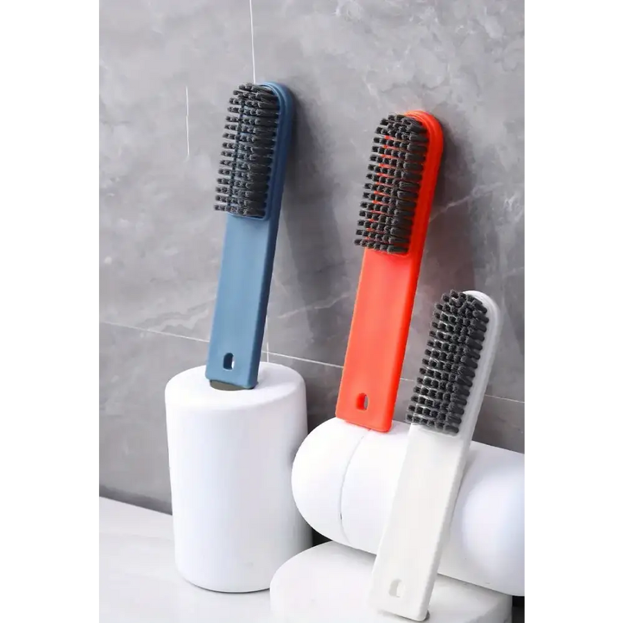 Three colorful scrub brushes with dense black bristles, featuring handles in blue, orange, and white plastic.