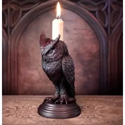 Dark bronze owl candle holder with intricate feather detailing and a lit white candle perched on its back.