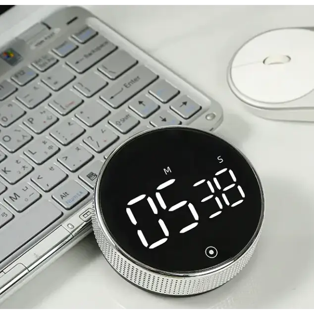 Silver digital timer with a black circular face displaying ’05:38’’ in white led numerals.